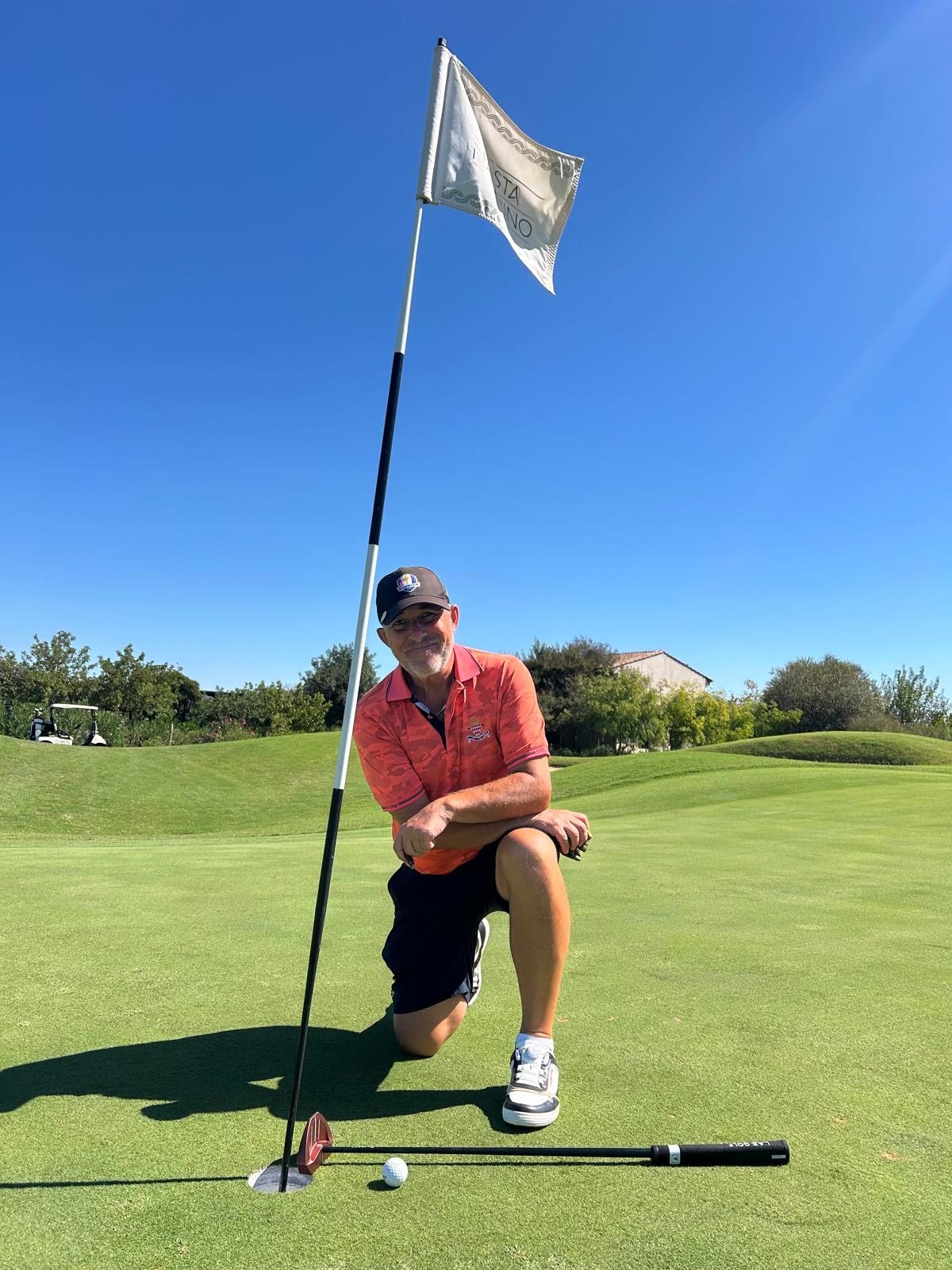 IGST member kneeling by the flag with the ball at the hole